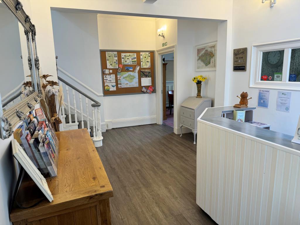 Lot: 102 - FREEHOLD GUEST HOUSE WITH 11 GUEST ROOMS AND SEPARATE OWNER'S ACCOMODATION - Reception area with desk and wood effect floor